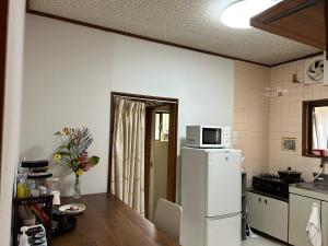 a kitchen with a white refrigerator and a microwave at ムラキン民泊 in Higashi-osaka