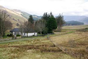 ein Haus mitten auf einem Feld mit einem Zaun in der Unterkunft Highland cottage Fort William in Fort William