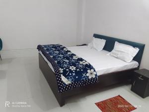 a bed with a blue and white blanket on it at Golden Lip Hotel in Bhiwadi
