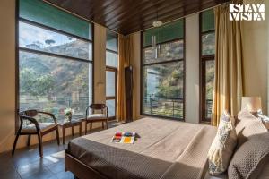 a bedroom with a bed and large windows at StayVista at The Marigold with BBQ & Bonfire in Kasauli