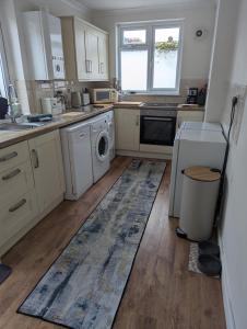 una cucina con armadi bianchi e un tappeto sul pavimento di Beach Walk Cottage a Walton-on-the-Naze