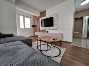 a living room with a table and a tv at Premium Central Skopje Apartments & Free Private Parking in Skopje