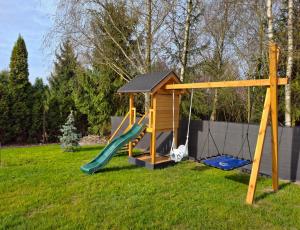 a playground with a slide and a swing at Świtówka - Domek z balią ogrodową in Żnin