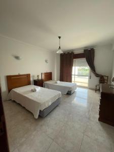a bedroom with two beds and a large window at cantinho do mar in Albufeira