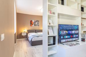 a bedroom with a bed and a tv and shelves at Isolino Bridge Apartment - Historic Center in Monza