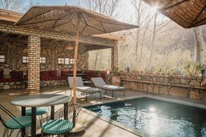 a patio with a table and chairs next to a pool at Chez Ichou in Aït Idaïr