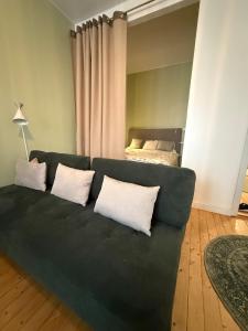 - un canapé vert avec des oreillers blancs dans le salon dans l'établissement Cozy studio in Punavuori, à Helsinki