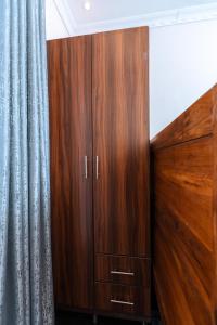 a wooden cabinet in a room with a curtain at Perfect Homes Namugongo in Kasiyirize +1 photo
