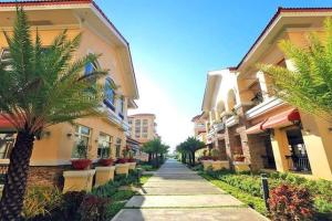 a walkway between two buildings with palm trees at San Remo Oasis in Cebu City