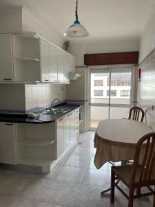 a kitchen with white cabinets and a table and a dining room at studio para 2 pessoas in Albufeira +9 photos
