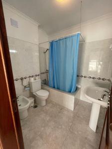 a bathroom with a toilet a sink and a blue shower curtain at studio para 2 pessoas in Albufeira