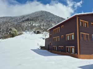 a building in the snow with a mountain in the background at Kaya Palace in Uzungöl