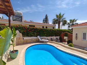 a swimming pool in front of a house at Villa Best Holiday- breathtaking sea views, amazing garden, private pool, BBQ, next to CORAL BAY, Lower Peyia, Paphos in Peyia