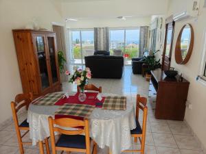 a dining room with a table and chairs and a living room at Villa Best Holiday- breathtaking sea views, amazing garden, private pool, BBQ, next to CORAL BAY, Lower Peyia, Paphos in Peyia