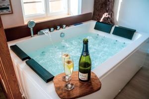 a bottle of champagne and two glasses in a bath tub at Nuit romantique, Suite avec jacuzzi et cinéma privé au design Japandi in Guebwiller