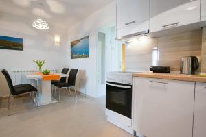 Una cocina con gabinetes blancos y una mesa con sillas. en Villa Mytilus, a beautiful villa with a fantastic sea view, en Trgetari