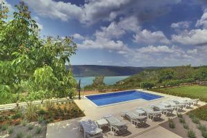 Una piscina con sillas y vista a un lago. en Villa Mytilus, a beautiful villa with a fantastic sea view, en Trgetari