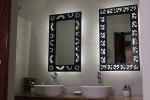 two sinks in a bathroom with two mirrors at La Créole APT10 in Toamasina