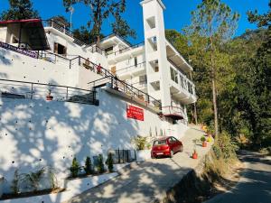 a red car parked in front of a white building at The Shalam Resort श्रीकृष्ण शरणं मम in Lansdowne