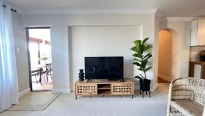 a living room with a flat screen tv on a table at Sorelle's Vista OR Luxury 1-Bedroom Apartment in Plettenberg Bay