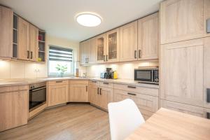 une grande cuisine avec des placards en bois et une table dans l'établissement Hafenkoje Ferienhaus Vareler Hafen, à Varel