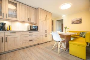 une cuisine avec des placards en bois, une chaise blanche et une table dans l'établissement Hafenkoje Ferienhaus Vareler Hafen, à Varel 21 autres photos