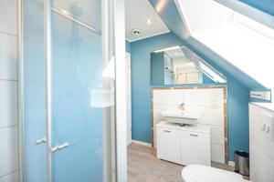 La salle de bains est pourvue d'un lavabo et d'un mur bleu. dans l'établissement Hafenkoje Ferienhaus Vareler Hafen, à Varel