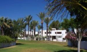 biały budynek z palmami na dziedzińcu w obiekcie Puerto Rey Apartamento 150m playa w mieście Los Amarguillos