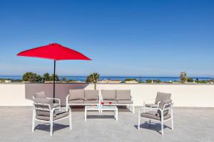 a group of chairs and a table with a red umbrella at Case Vacanza Loria in Castelluzzo