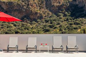 four chairs and a table with a red umbrella at Case Vacanza Loria in Castelluzzo
