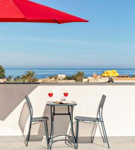 a table with two chairs and a red umbrella at Case Vacanza Loria in Castelluzzo