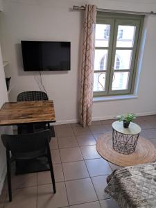 a living room with a table and a tv on the wall at STUDIO 1 personne dans le centre historique in Le Puy-en-Velay