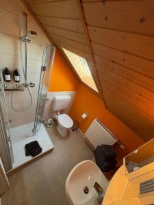 an attic bathroom with a shower and a toilet at RelaxStay - Weserbergland in Heinsen