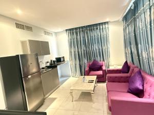 a living room with two pink couches and a kitchen at Swan Towers Juffair in Manama