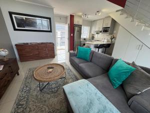 una sala de estar con un sofá y una mesa en Stylish Loft apartment in the heart of Durbanville, en Durbanville