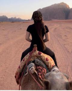 eine Frau, die auf dem Rücken eines Elefanten in der Wüste reitet in der Unterkunft Rum Gonesh Luxury Camp in Wadi Rum