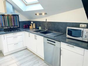 a kitchen with a sink and a microwave at Le Sweet Home, clim, parking privé, wifi in Reims