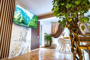 a living room with a tv on the wall and a tree at Almi Aparthotel in Cluj-Napoca