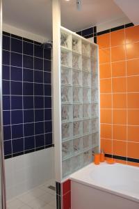La salle de bains est pourvue de murs carrelés bleu et orange et d'une baignoire. dans l'établissement Au Coeur De Beauvais, à Beauvais