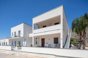 a white house with a staircase and palm trees at Case Vacanza Loria in Castelluzzo
