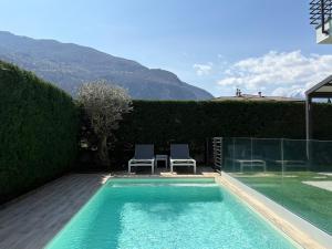 a swimming pool with two chairs next to a house at Serenity villa - Lake Como in Colico