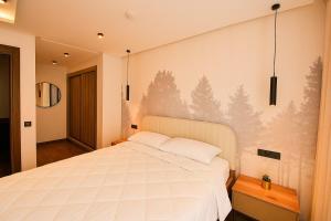 a bedroom with a white bed with a pine tree mural at Atelier Aedes - Studio 15 in Maarif