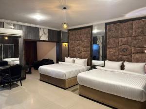 a hotel room with two beds and a desk at Hotel Oasis in Islamabad