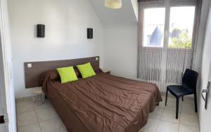 a bedroom with a bed with two lime green pillows at Les Coquillages in Trégastel
