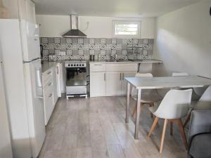 a kitchen with white cabinets and a table with chairs at Appartement Le Maro in Saubusse