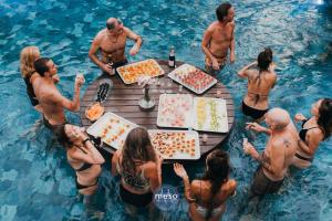 a group of people standing around a table in the water at Marbela Beach Resort in Morjim