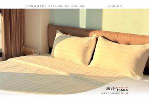un letto con lenzuola e cuscini bianchi di 西衛參零陸民宿 Xiwei 306 Inn a Magong