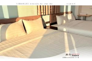 due letti in una camera d'albergo con lenzuola bianche di 西衛參零陸民宿 Xiwei 306 Inn a Magong Altre 26 foto