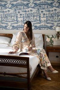 a woman sitting on a bed with a cup of coffee at Palace Hotel in Viareggio
