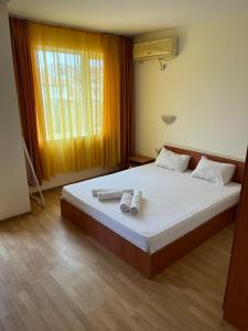 a bedroom with a bed with two towels on it at Хотел Стоянови in Ravda